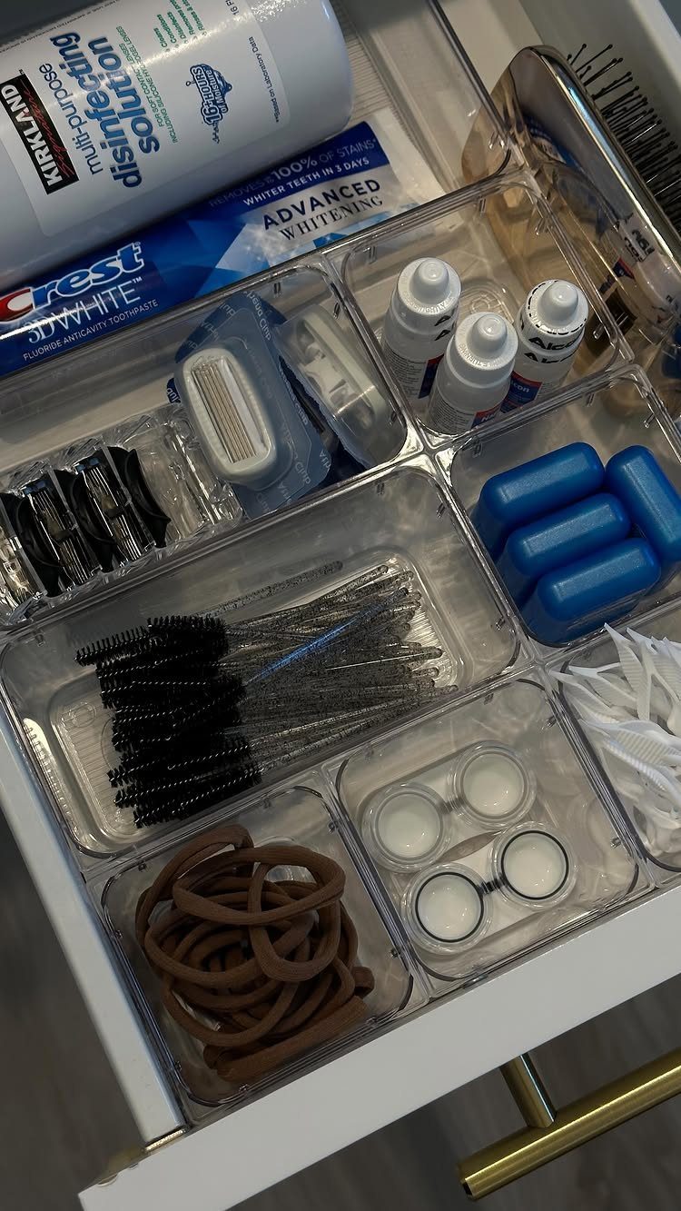 28 Bathroom Cabinet Ideas Storage Fixes for Small Spaces 2 Clear plastic drawer organizers holding various toiletries inside a white bathroom vanity drawer.