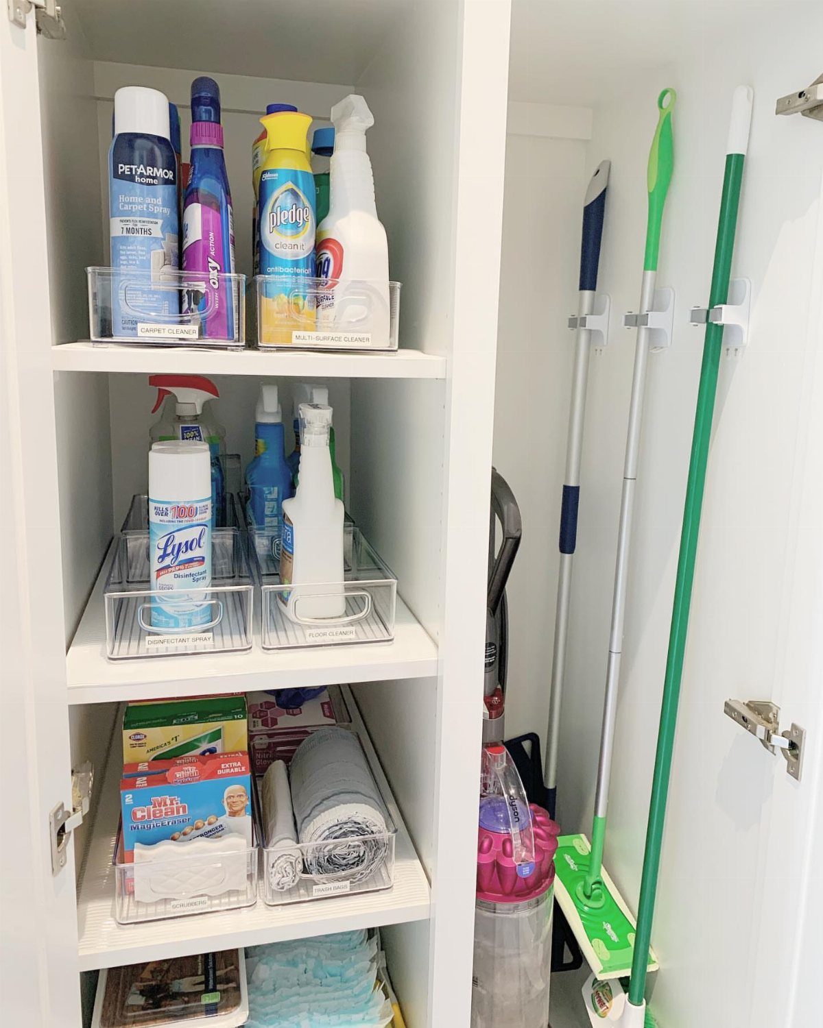 10 Broom Closet Design Ideas for Laundry Rooms and Stairs 4 White broom closet with cleaning supplies on shelves and mops held by wall clips.