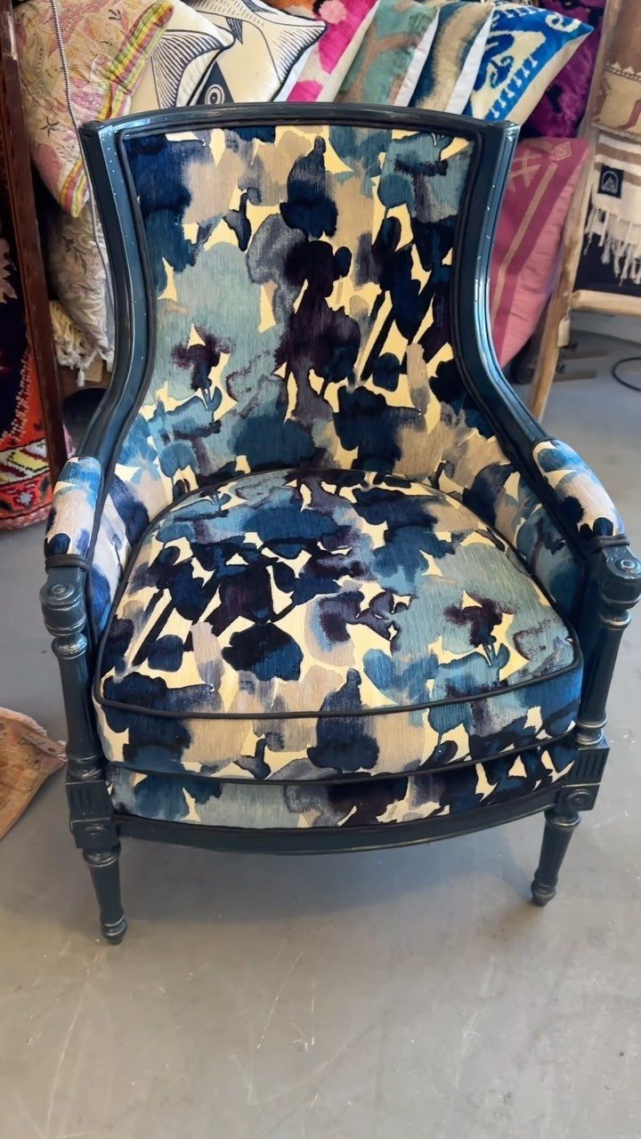 Blue armchair with abstract navy and light blue patterned upholstery and dark frame.