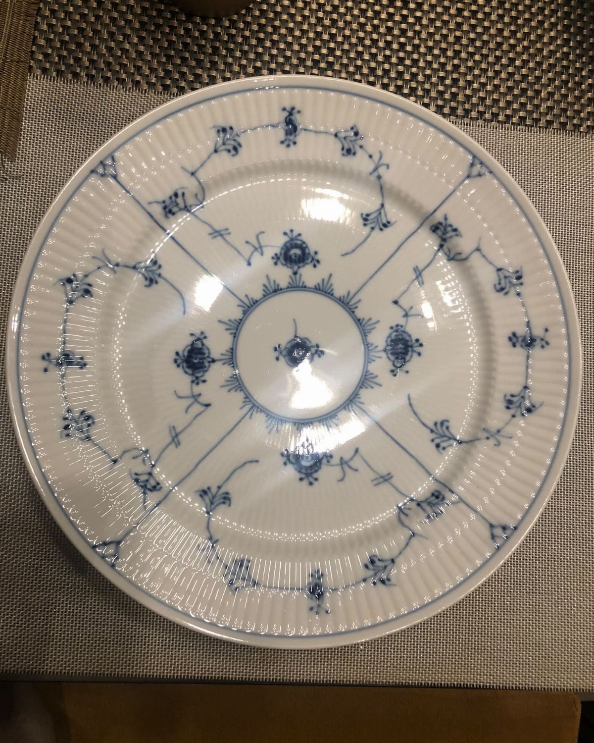 White china plate with blue floral patterns resting on a grey textured placemat.