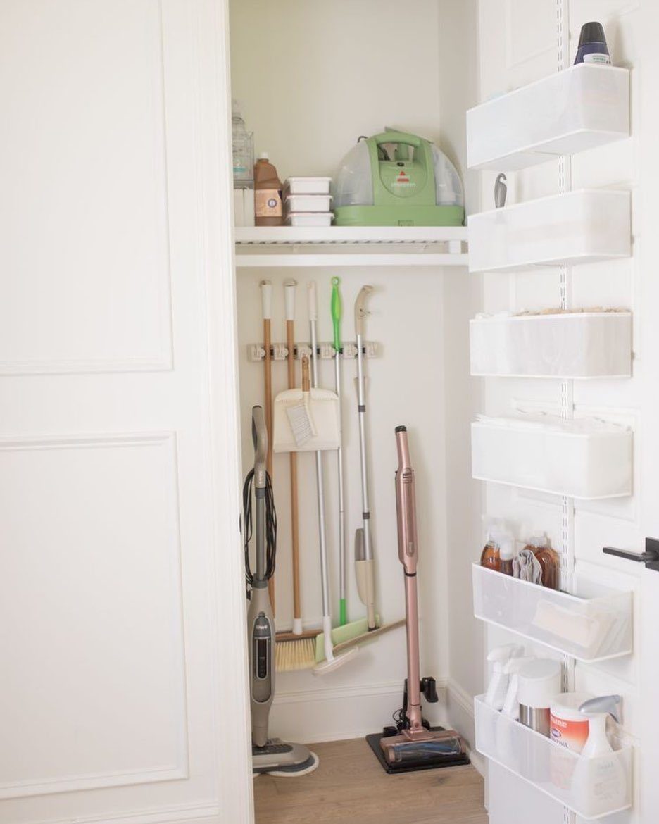 10 Broom Closet Design Ideas for Laundry Rooms and Stairs 6 White clear pocket organizer on a closet door holding various cleaning spray bottles.