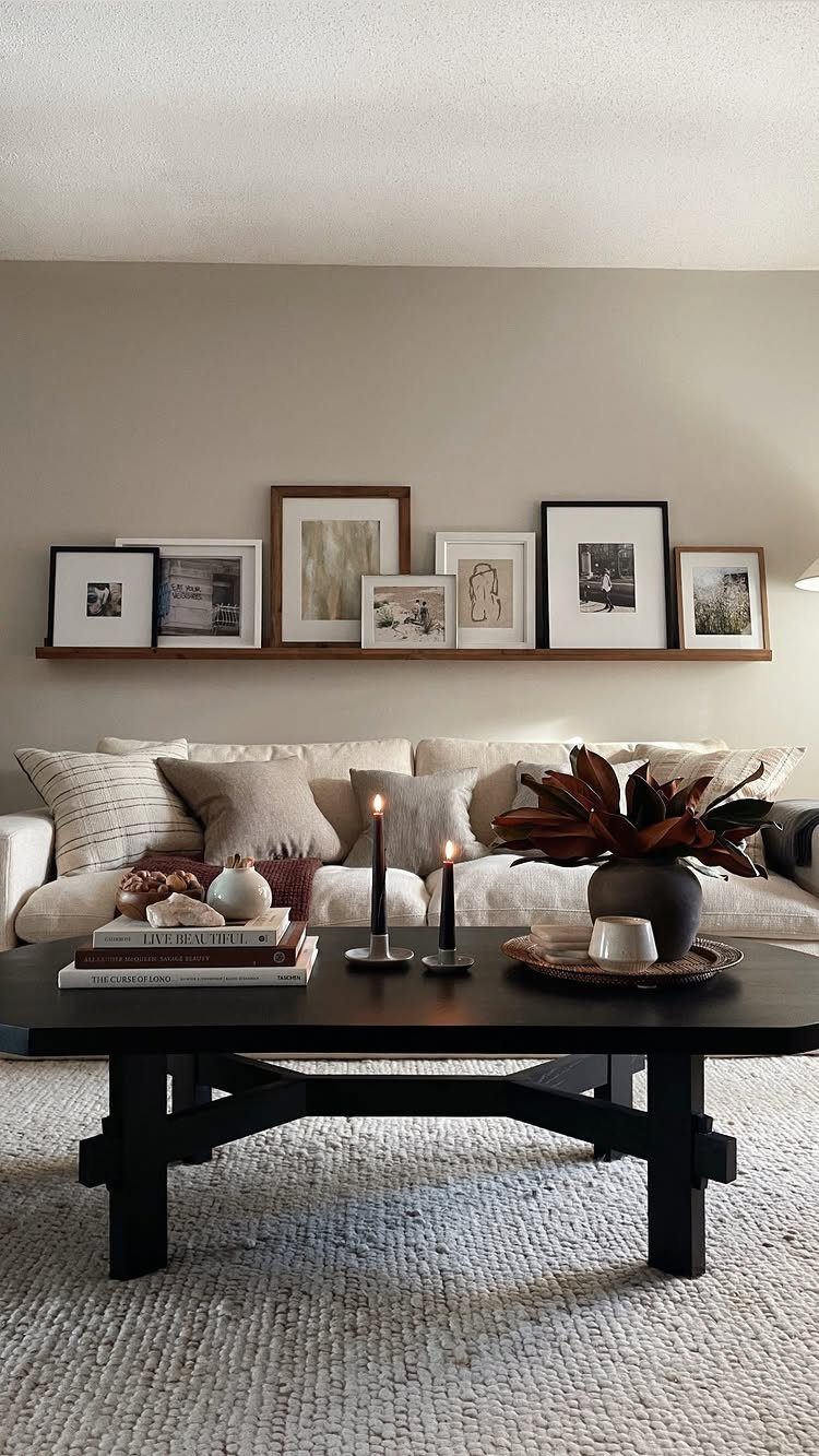 Dark wood coffee table styled with books, candles, and dried leaves in a living room.