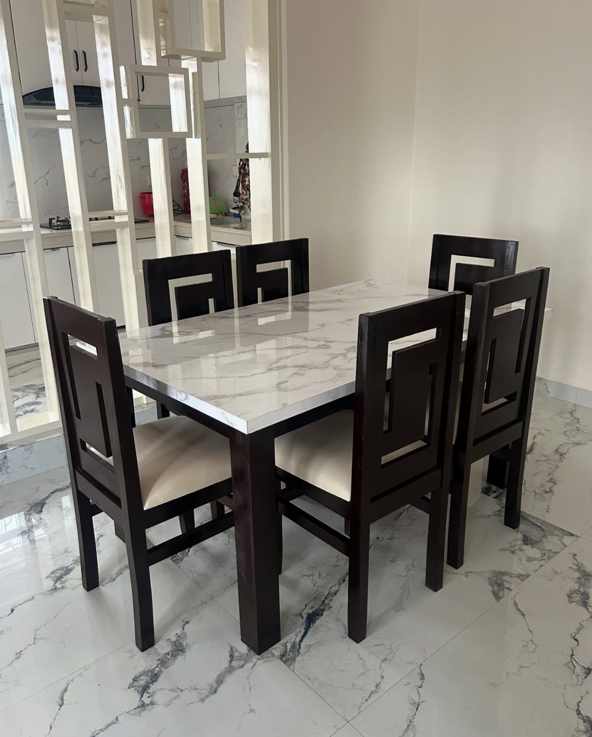Dark wood dining table with marble top and four matching cushioned chairs.