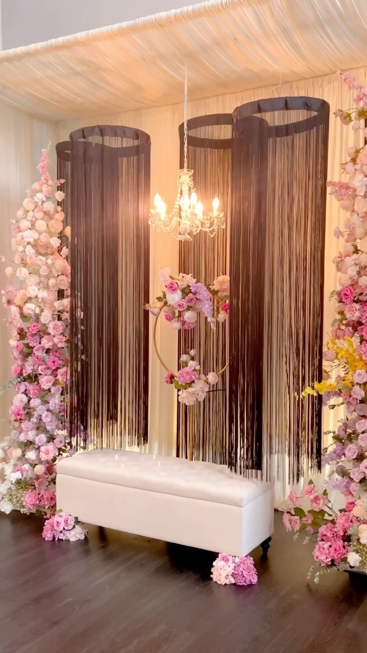 28 Wedding Decorations Ideas at Home with Flowers and Lights 12 White bench and crystal chandelier in front of shimmering dark curtains and pink flowers