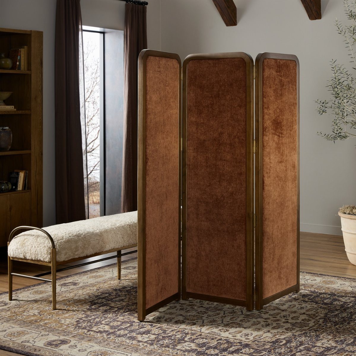 Three-panel folding room divider with brown fabric and dark wood frame on a rug.