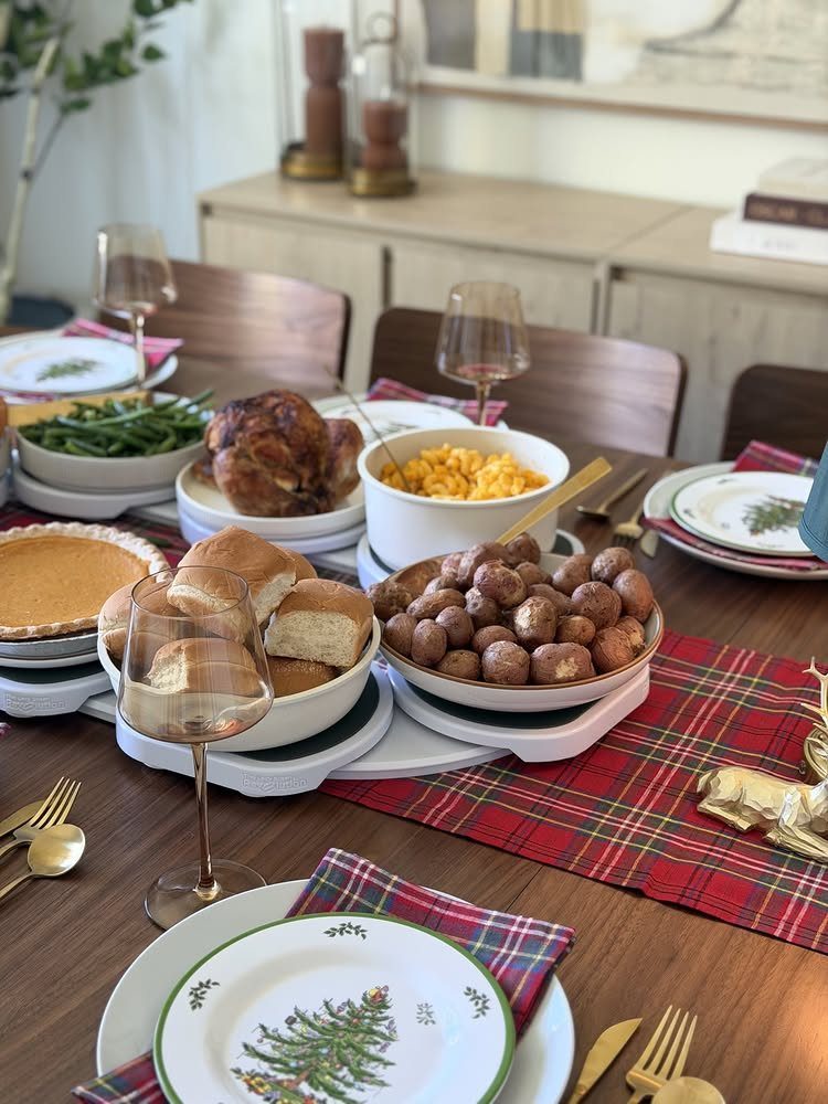 Christmas dinner table with roasted turkey, side dishes, and red plaid decorations.