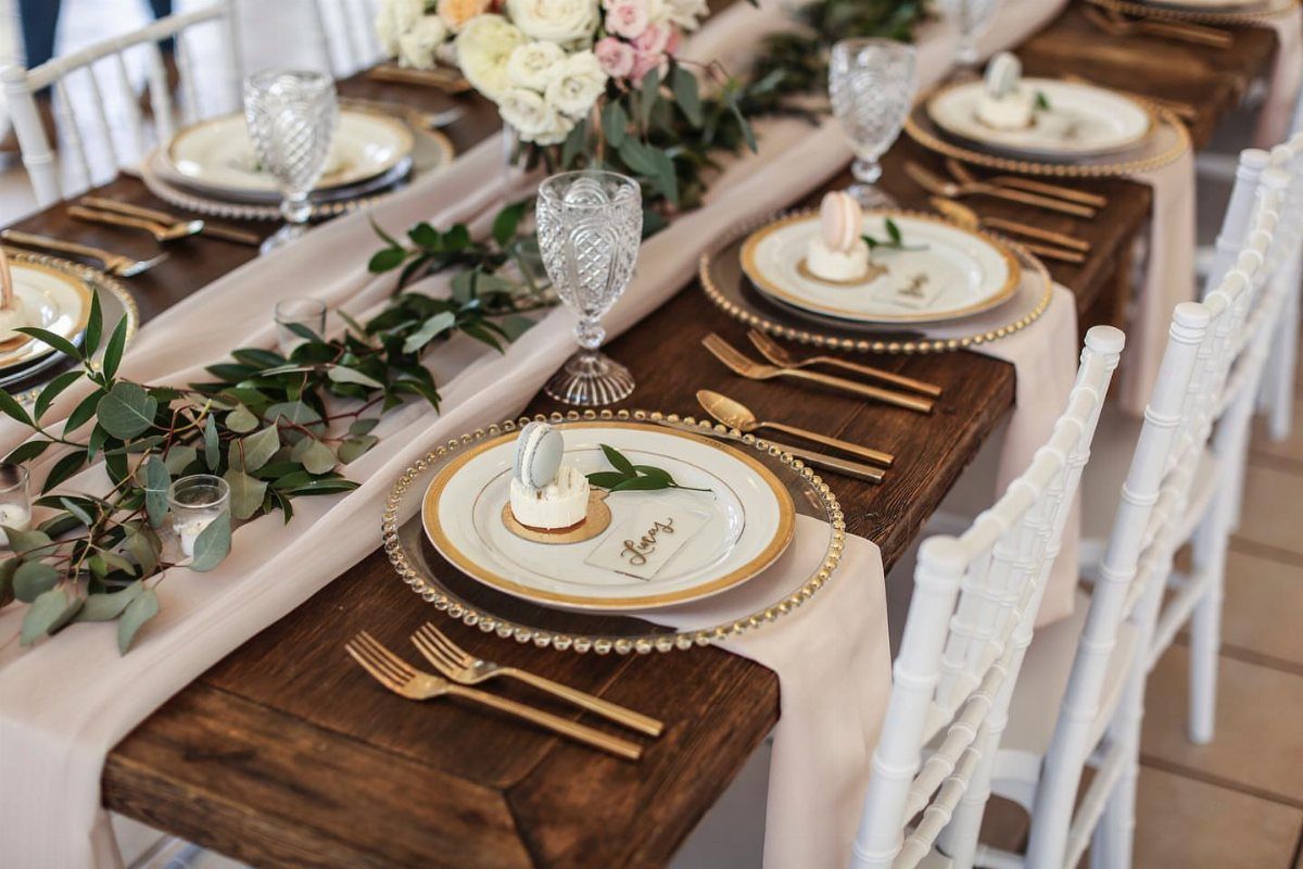 Gold and White Table Decor: 20 Ideas for Parties and Events 12 Gold beaded charger plates under white dinnerware on a wooden table with floral greenery.