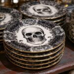 Stacks of black and white gothic plates featuring central skull illustrations and gold rims.