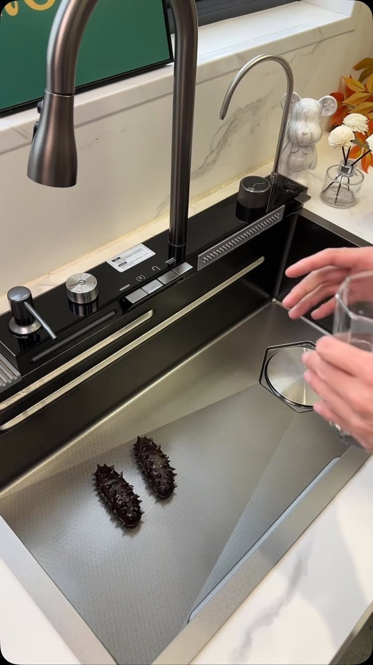 Black stainless steel kitchen sink with a pull-down faucet and waterfall spout.