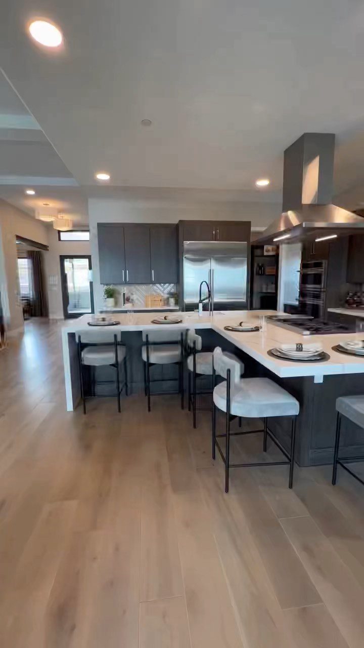 Kitchen Island with Seating on Two Sides: 10 Layout Ideas 7 L-shaped kitchen island with white countertops and grey stools in a modern kitchen.