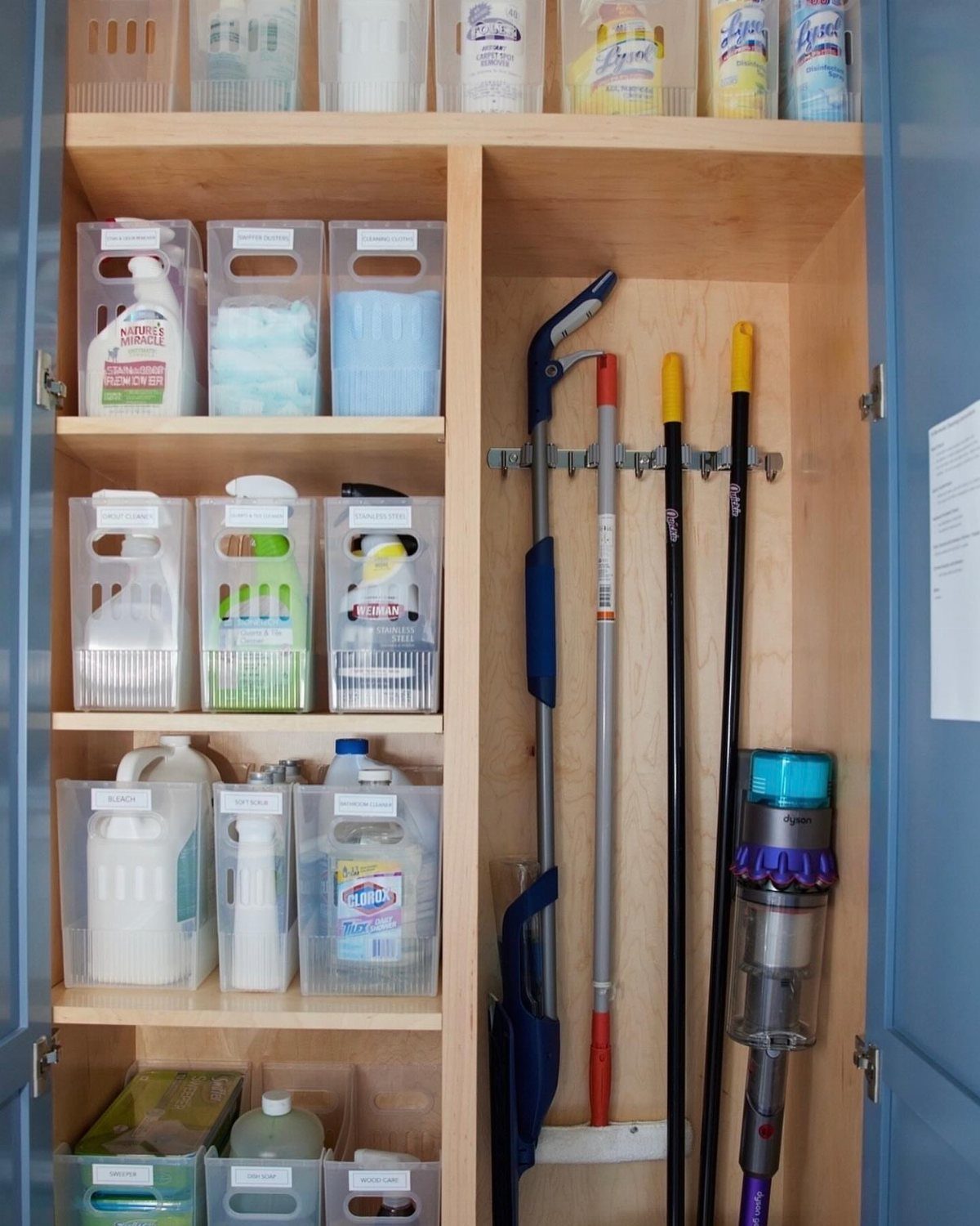 10 Broom Closet Design Ideas for Laundry Rooms and Stairs 5 Organized broom closet with labeled clear bins and cleaning tools on a rack.
