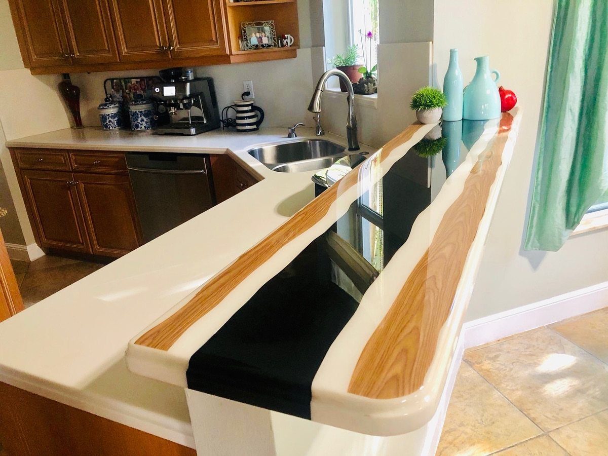 White kitchen countertop with a black glossy river center and natural wood borders.