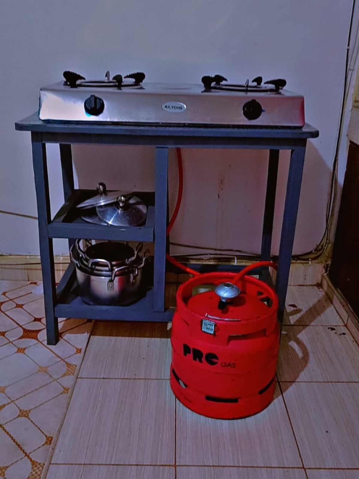 12 Gas Cooker Table Ideas, From Portable to Built-In Models 8 Silver gas stove on a grey wooden table with a red gas cylinder below.