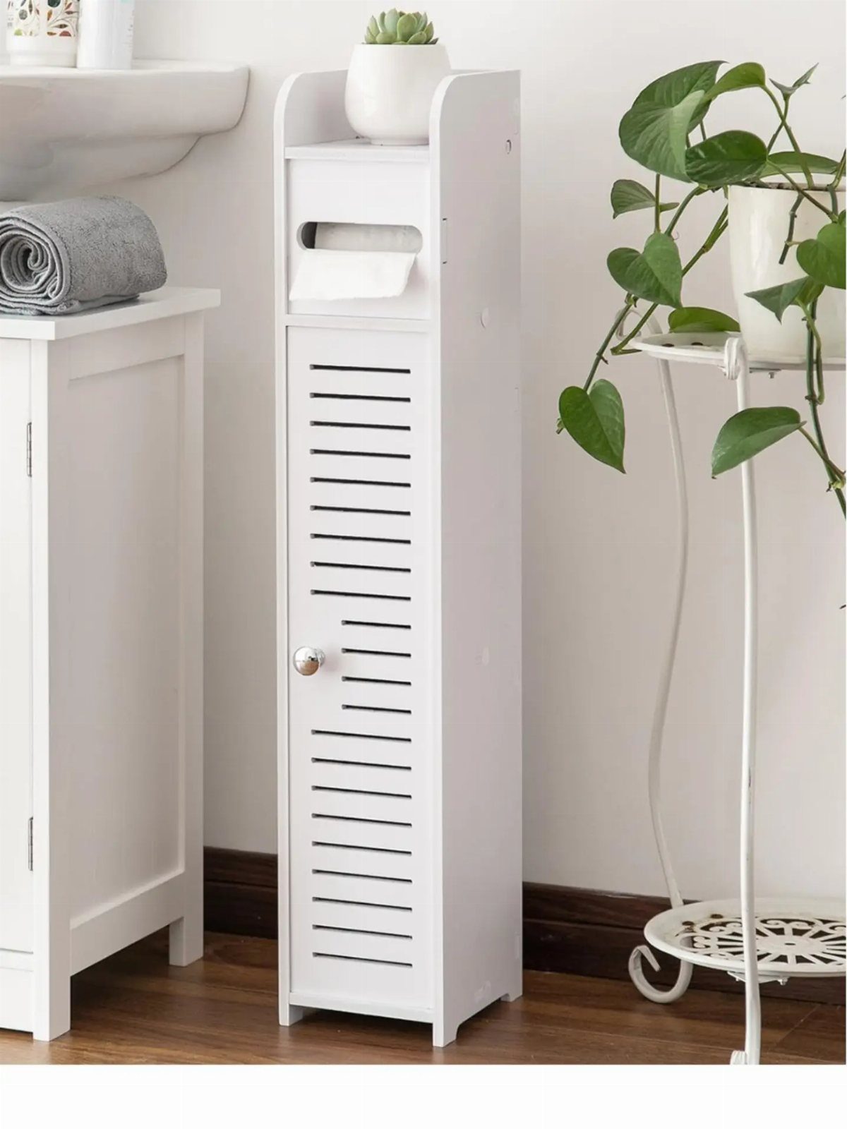 28 Bathroom Cabinet Ideas Storage Fixes for Small Spaces 23 Slim white bathroom storage cabinet with slatted door and top shelf for plants.