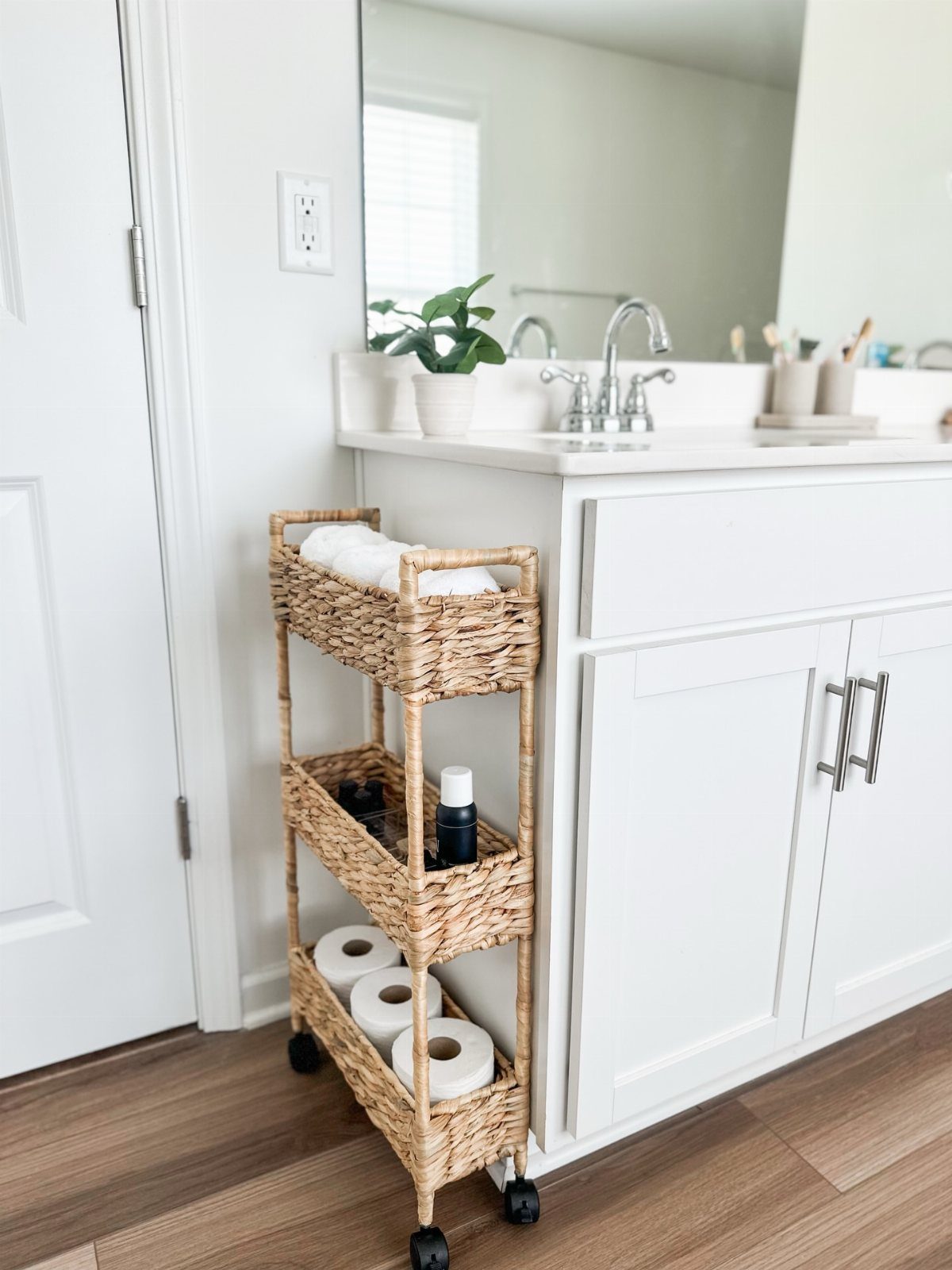 28 Bathroom Cabinet Ideas Storage Fixes for Small Spaces 7 Woven wicker slim rolling cart with three tiers next to a white bathroom vanity.
