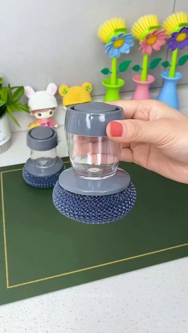 Soap dispenser with a blue scrubbing brush on a dark green kitchen mat.