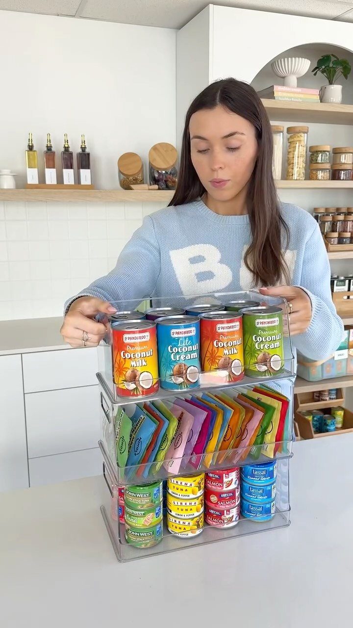 17 Kitchen Snack Storage Ideas for Pantries and Counters 2 Clear stackable plastic bins containing canned coconut milk and colorful snack packets.