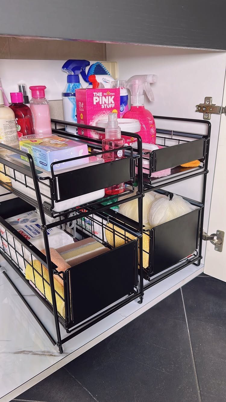 28 Bathroom Cabinet Ideas Storage Fixes for Small Spaces 15 Black wire storage baskets holding cleaning supplies inside a white bathroom cabinet.