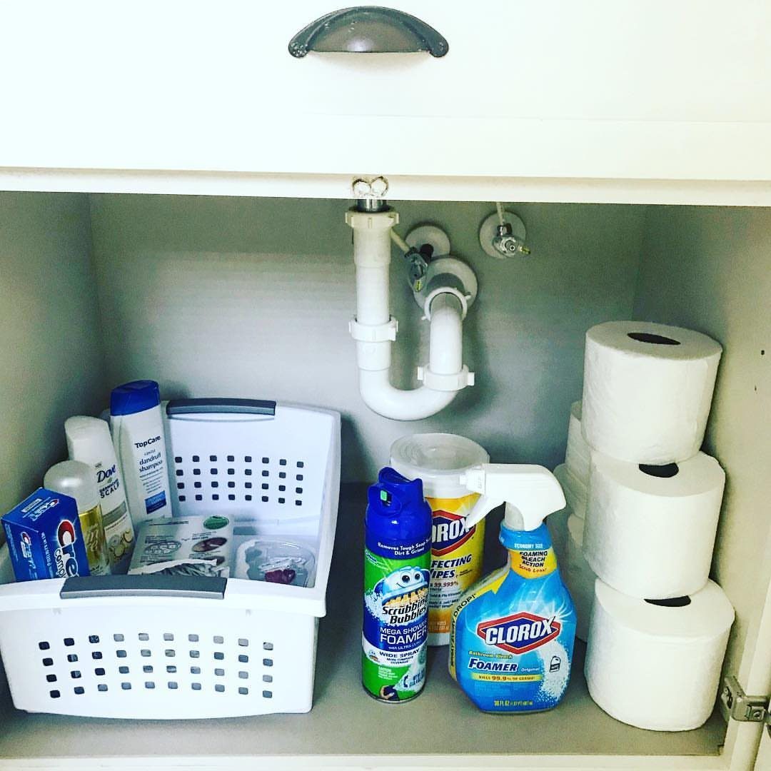 28 Bathroom Cabinet Ideas Storage Fixes for Small Spaces 19 White plastic storage bin and cleaning supplies inside a bathroom vanity cabinet.