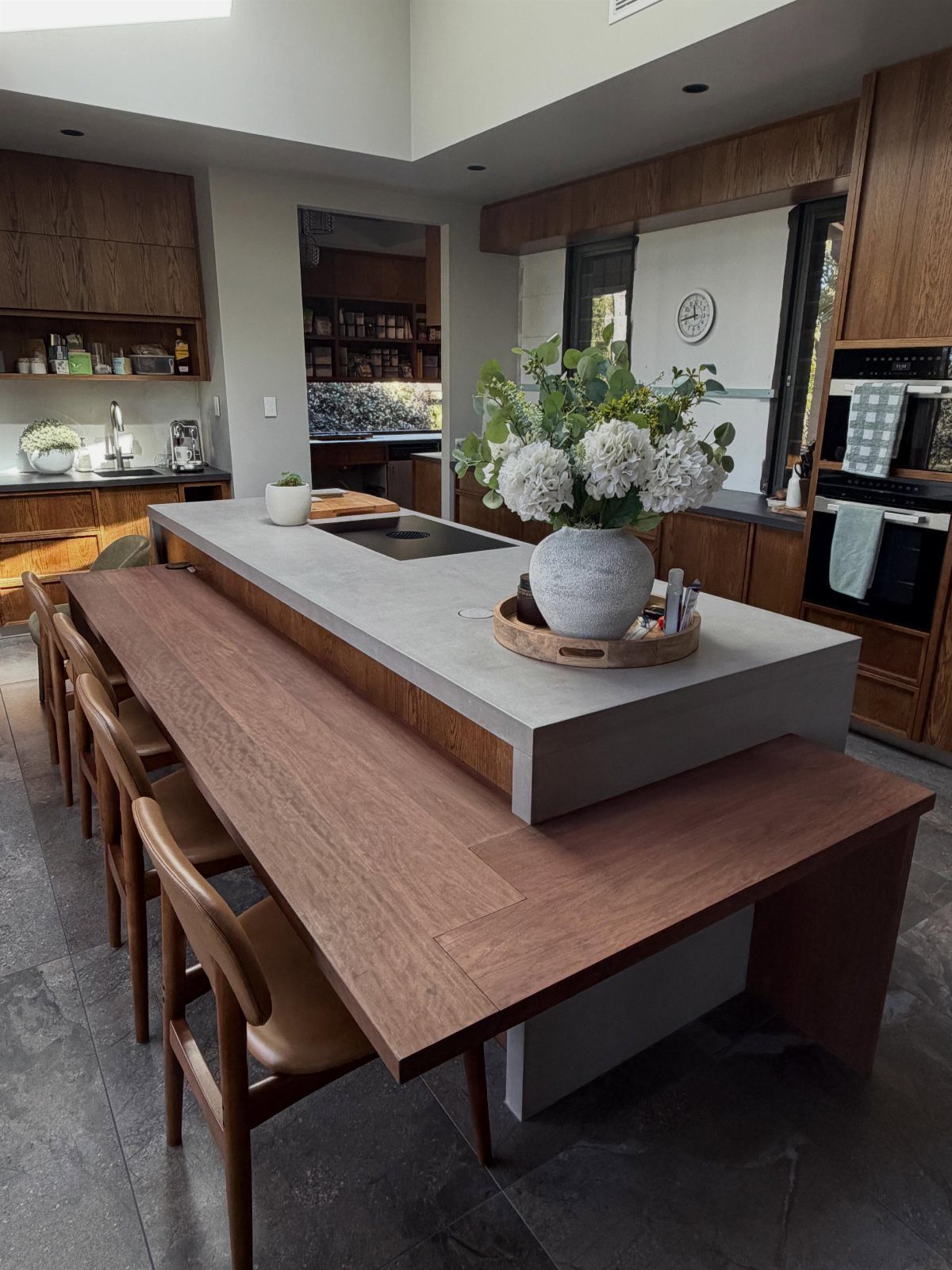 Kitchen Island with Seating on Two Sides: 10 Layout Ideas 6 Concrete kitchen island with a lowered wooden table end and brown leather chairs.
