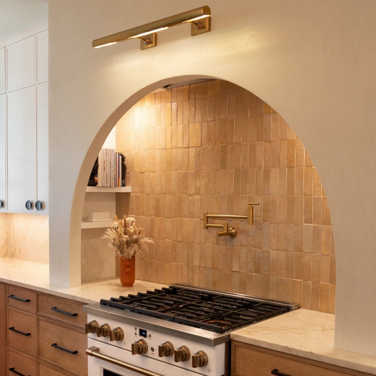 40 Small Kitchen Setup Ideas for Layouts, Storage and Style 37 Arched kitchen alcove with tan vertical tiles, gold pot filler, and white stove.