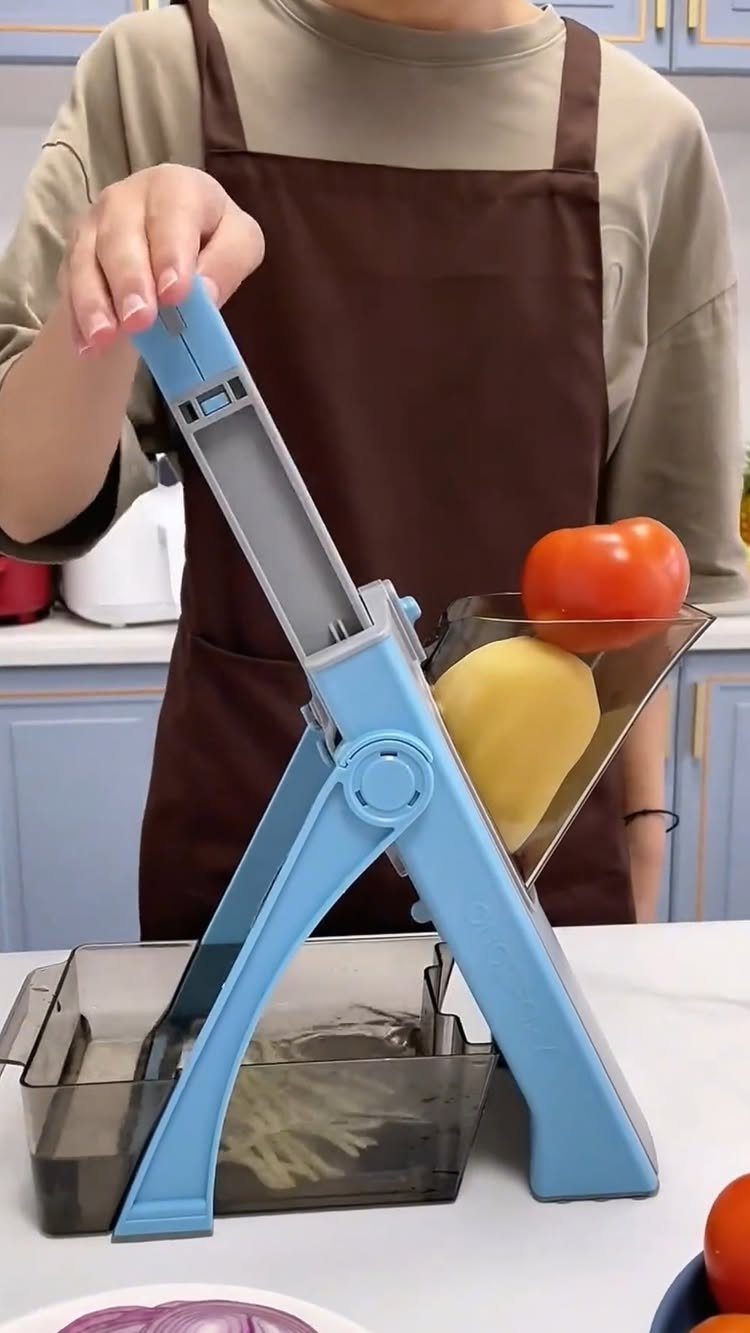 Light blue vegetable mandoline slicer with a potato and tomato and collection bin.