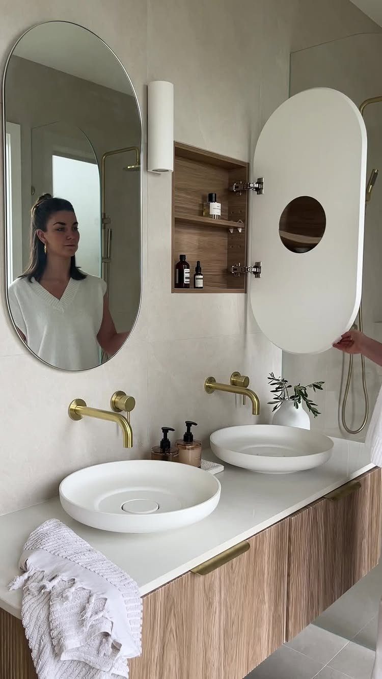 28 Bathroom Cabinet Ideas Storage Fixes for Small Spaces 8 Small wooden wall cabinet with shelves next to an oval bathroom mirror and sinks.