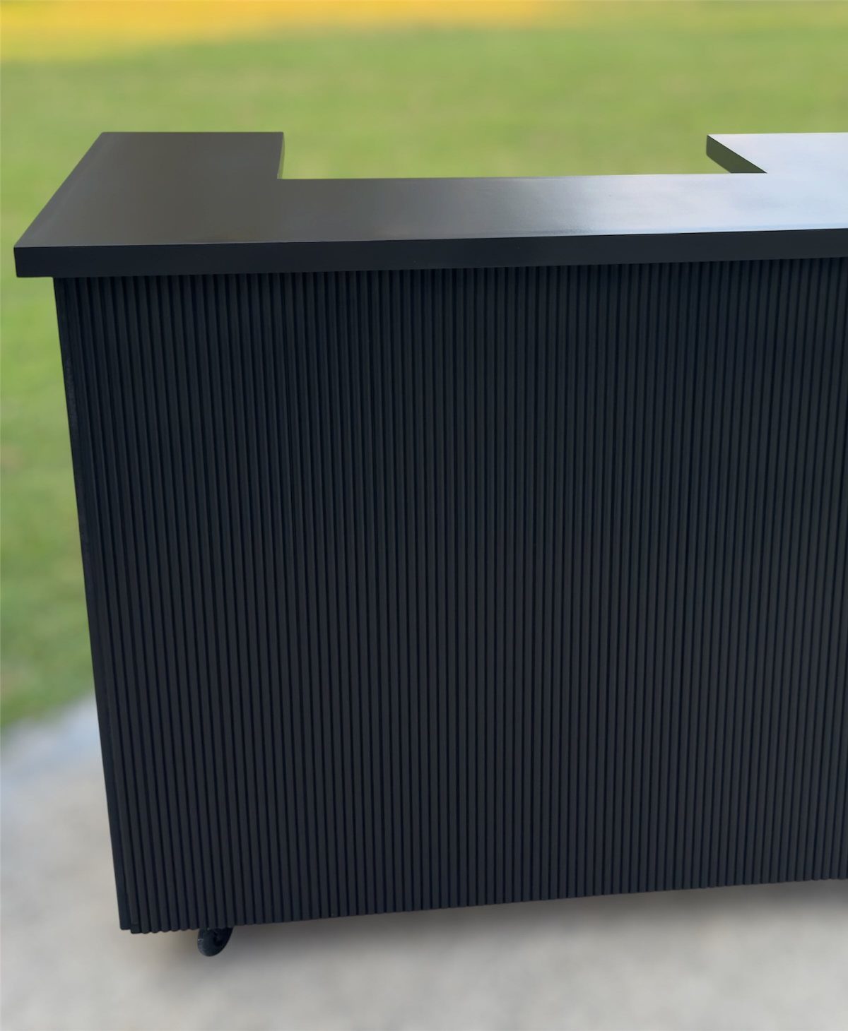 Movable Bar Counter Ideas: 8 Portable, Rolling and Home Styles 8 Black fluted movable bar counter with wheels on a concrete surface outdoors.