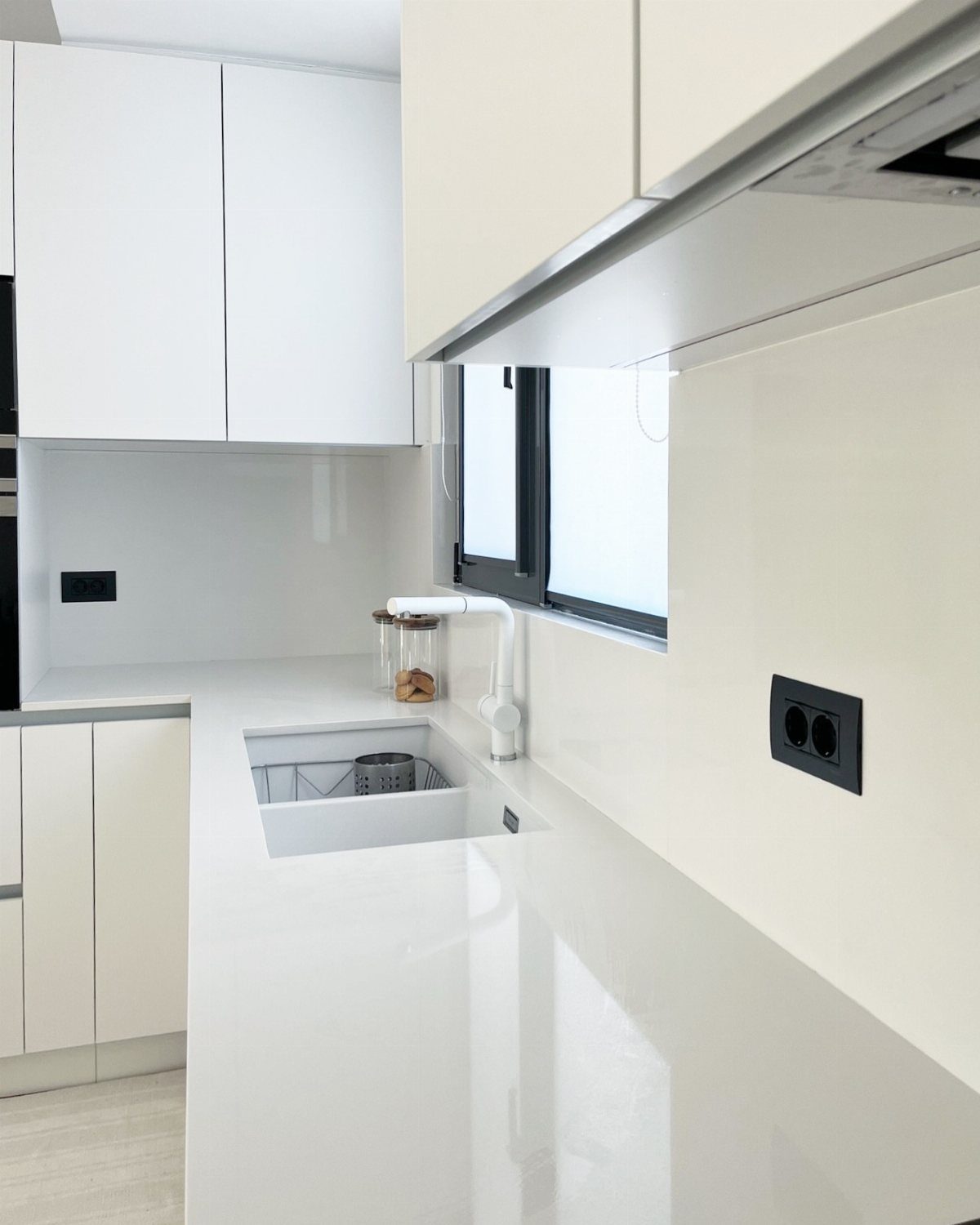 White porcelain countertop in a bright modern kitchen with matching white cabinetry.