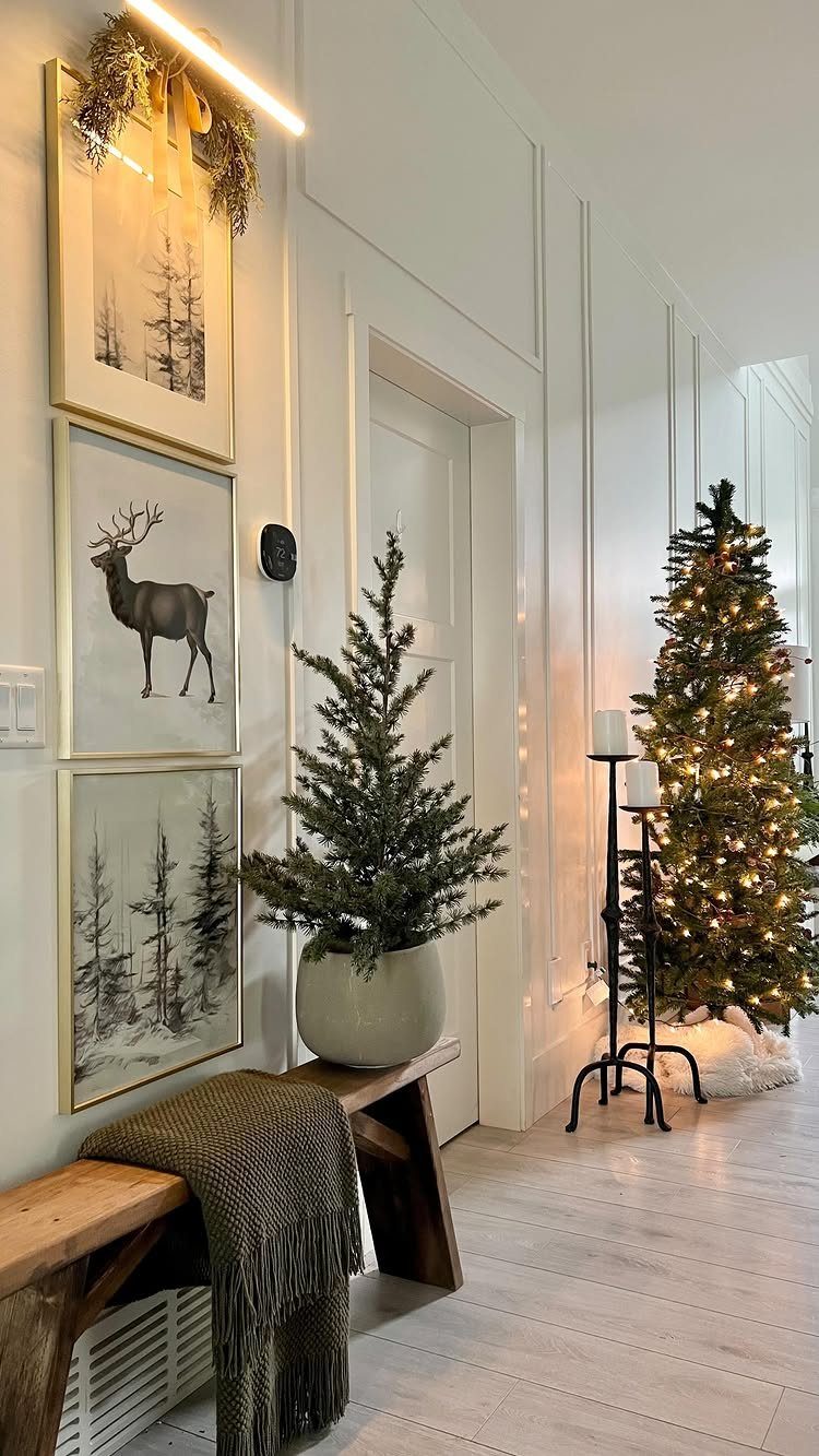 Three framed winter forest and deer art prints hanging on a white wall.